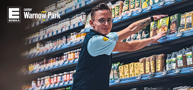 Mitarbeiter in Arbeitskleidung für Unternehmen ordnet Regale im Edeka Markt