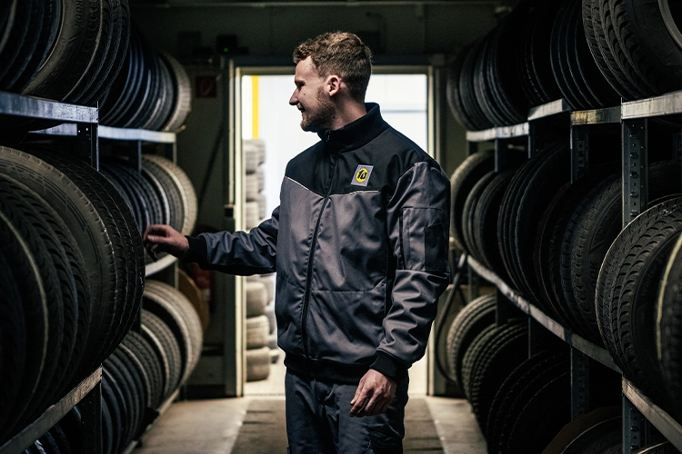 1A Autoservice Mitarbeiter in Berufsbekleidung zwischen Reifenregalen