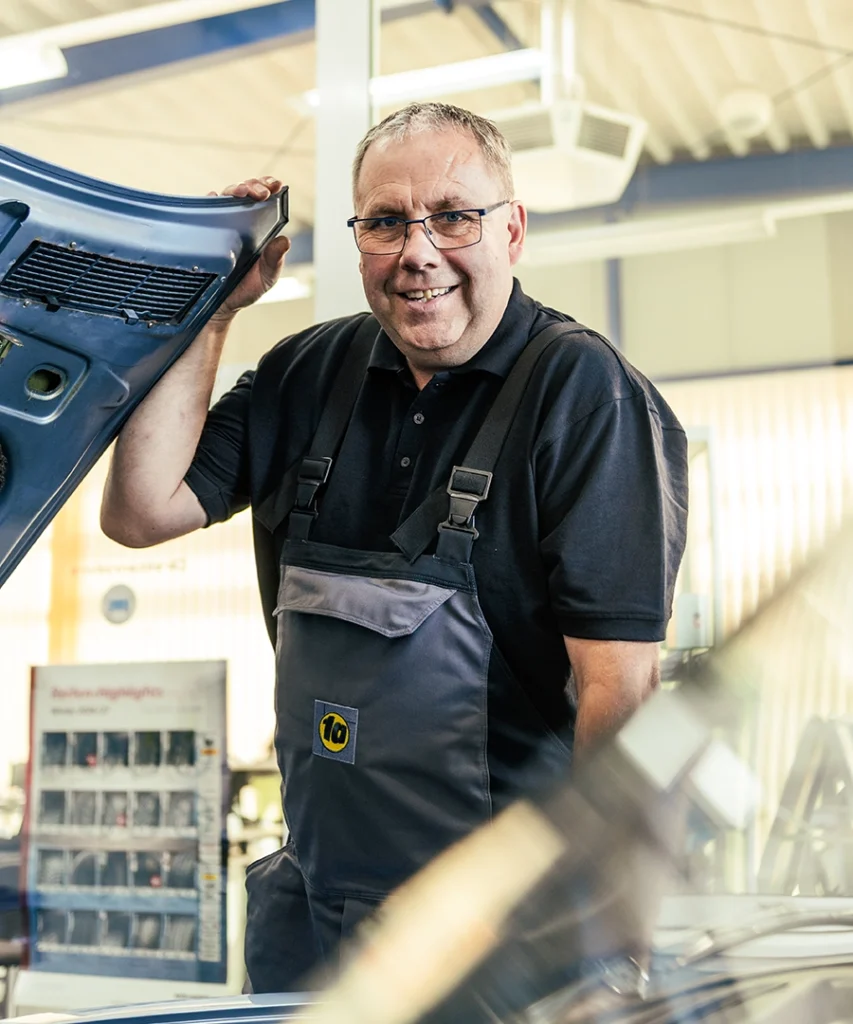 Mechaniker in 1A Autoservice Berufsbekleidung arbeitet an einem Auto