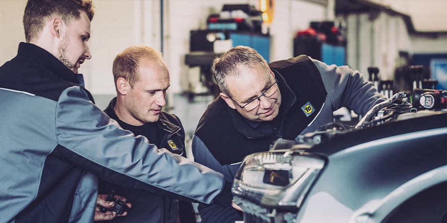 Mitarbeiter in 1A Autoservice Berufsbekleidung überprüfen ein Fahrzeug